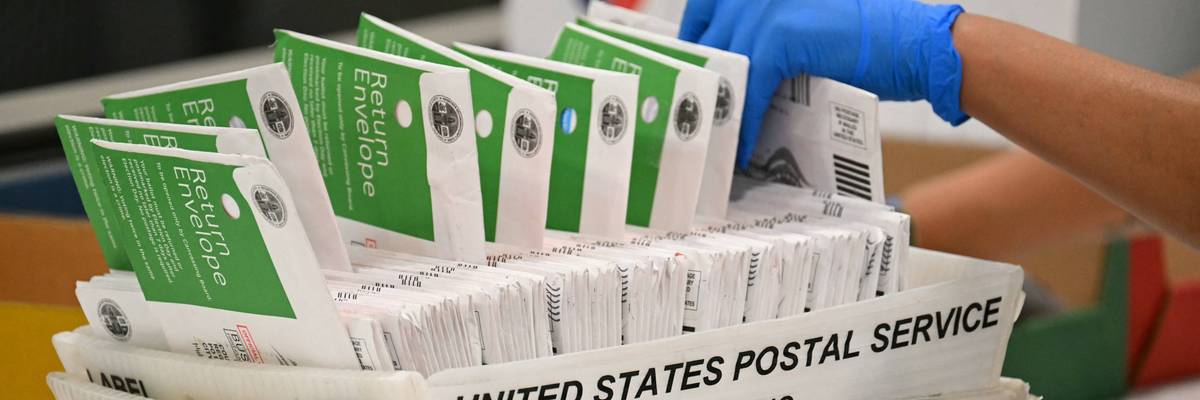 A postal worker processes mail-in ballots.