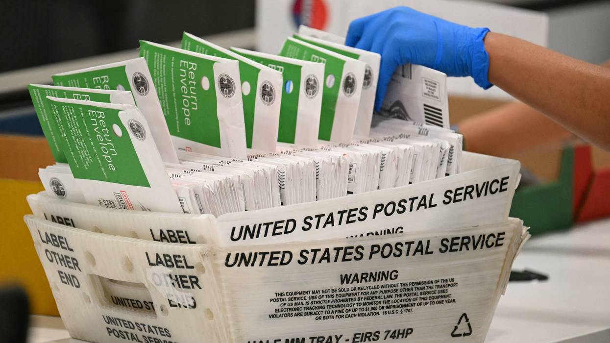 A postal worker processes mail-in ballots.
