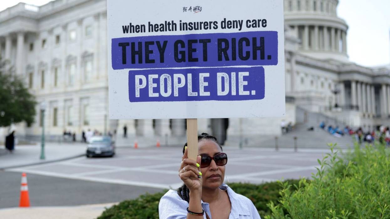 A poster held up against the U.S. Capitol building reading, "When health insurers deny care, they get rich. People die.'