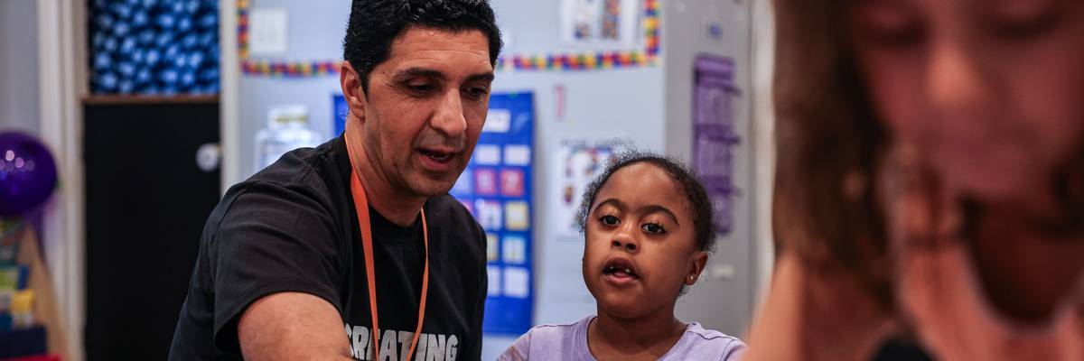 A preschool teacher works with a student