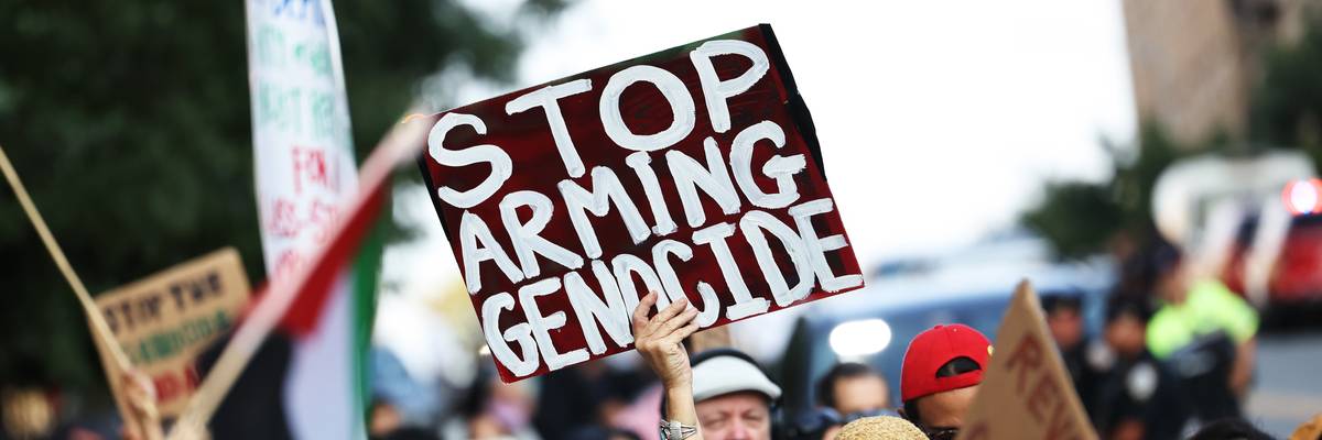 A pro-Palestinian activist holds a sign reading, "Stop arming genocide."
