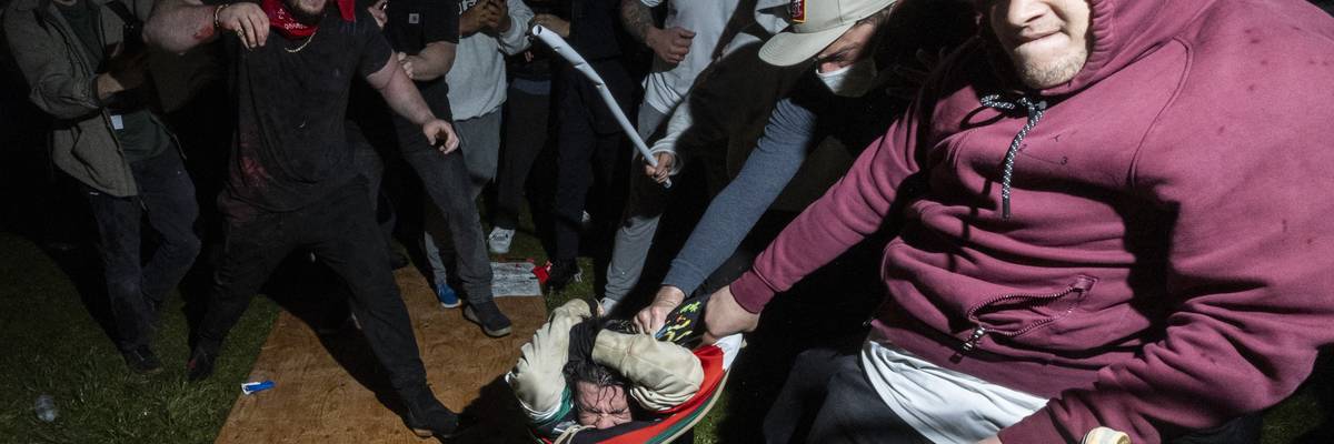 A pro-Palestinian demonstrator is beaten by a pro-Israel mob