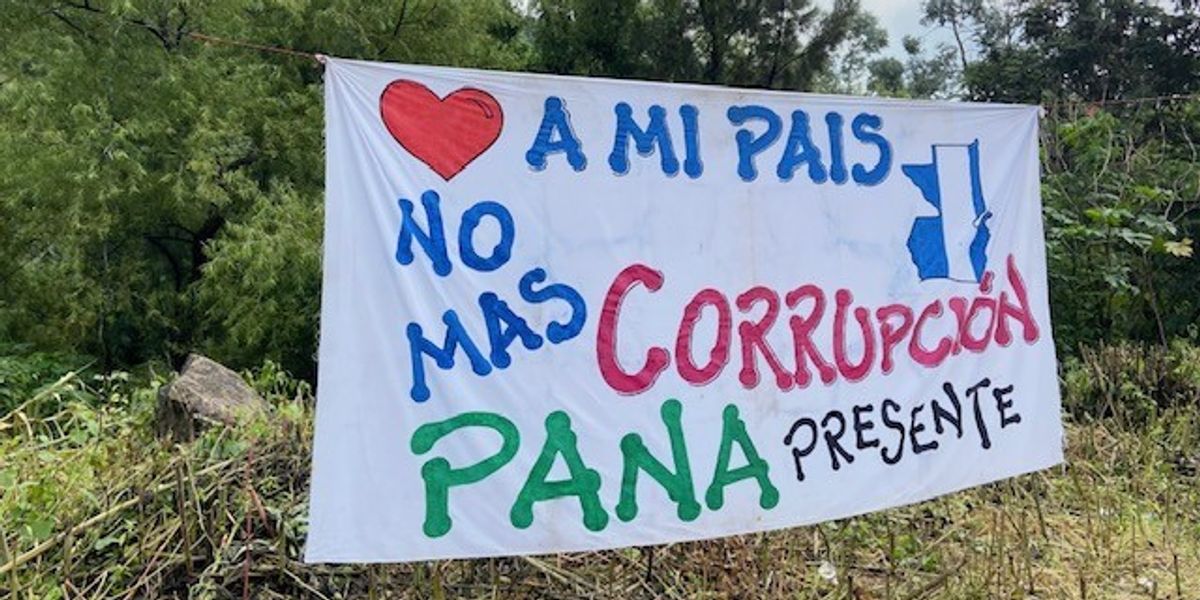 A protest sign reading, "I love my country. No more corruption. Pana represent," in Spanish.