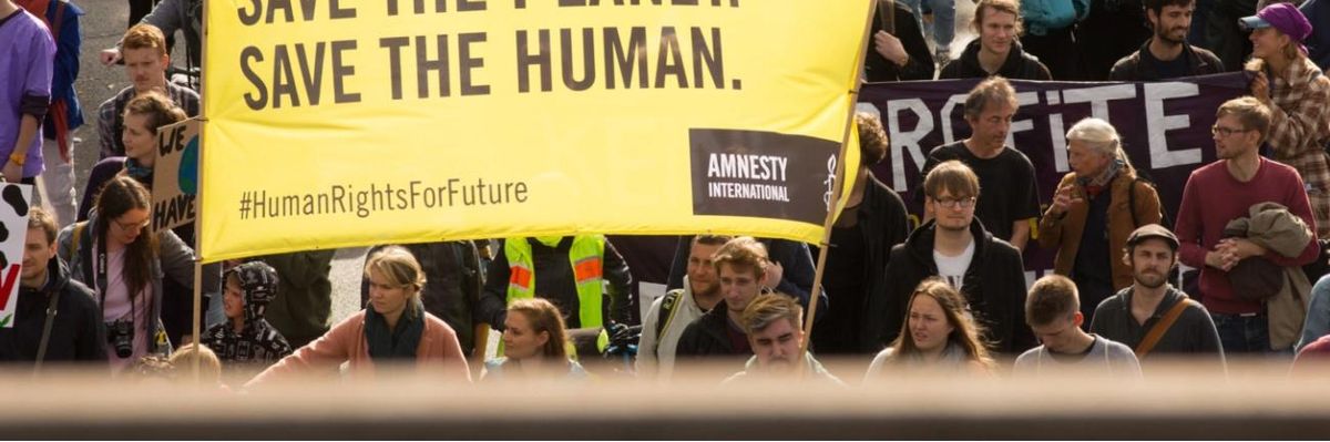 A protest sign reads "Save the Planet, Save the Human"