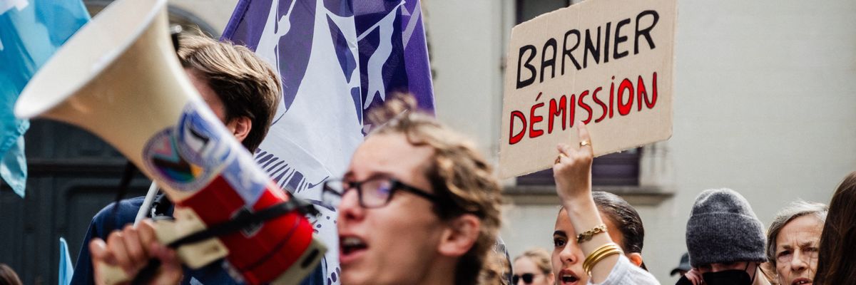 A protester carries a sign called on Michel Barnier, who was selected by French President Emmanuel Macron as the prime minister, to resign