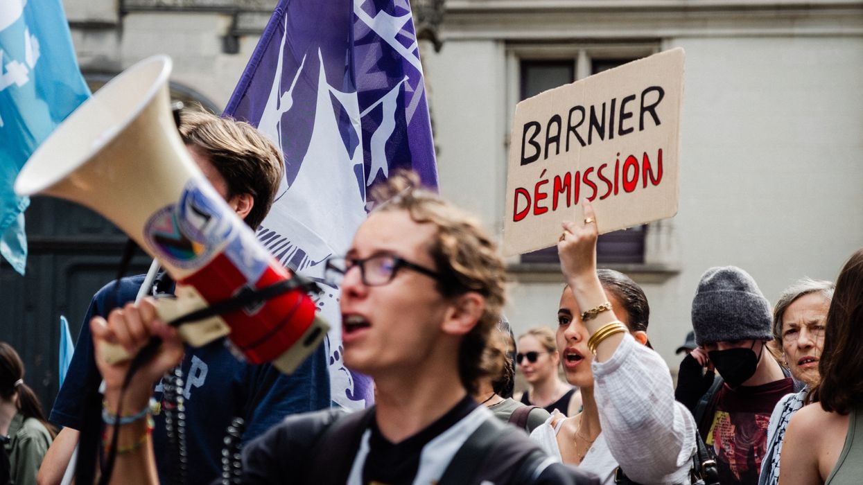 A protester carries a sign called on Michel Barnier, who was selected by French President Emmanuel Macron as the prime minister, to resign