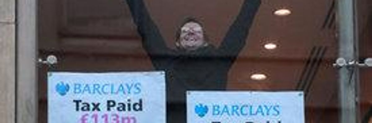 A protester from UK Uncut raises his arms as he takes part in an occupation of a branch of Barclays bank in central London. 