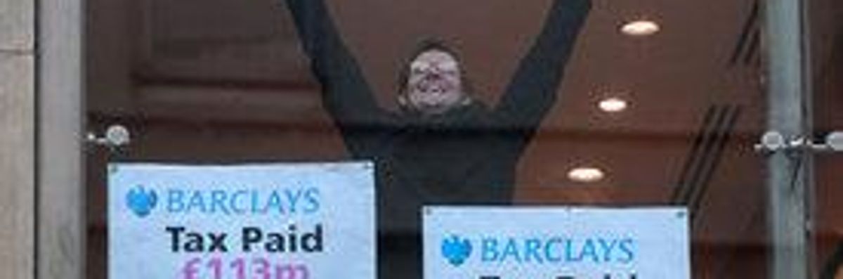 A protester from UK Uncut raises his arms as he takes part in an occupation of a branch of Barclays bank in central London.