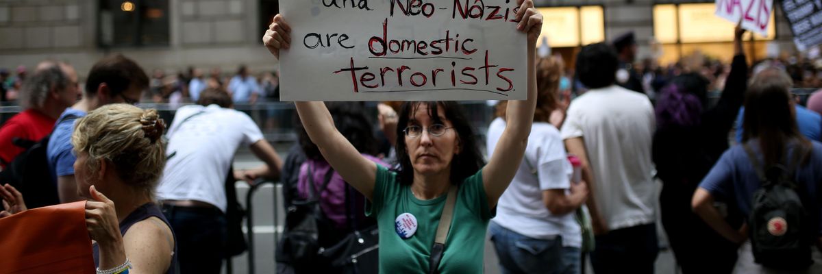 A protester holds a banner reading "The KKK and Neo-Nazis Are Domestic Terrorists" during a rally against then-U.S. President Donald Trump on August 14, 2017 in New York City. (Photo: Mohammed Elshamy/Anadolu Agency via Getty Images)