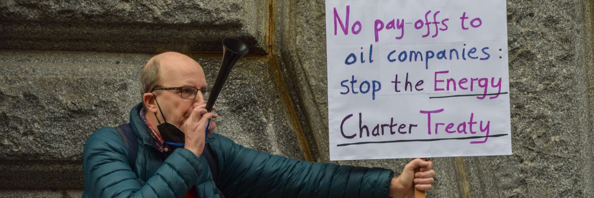A protester holds a placard calling for the abolition of the Energy Charter Treaty during a Global Day of Action for Climate Justice demonstration in London on November 6, 2021.