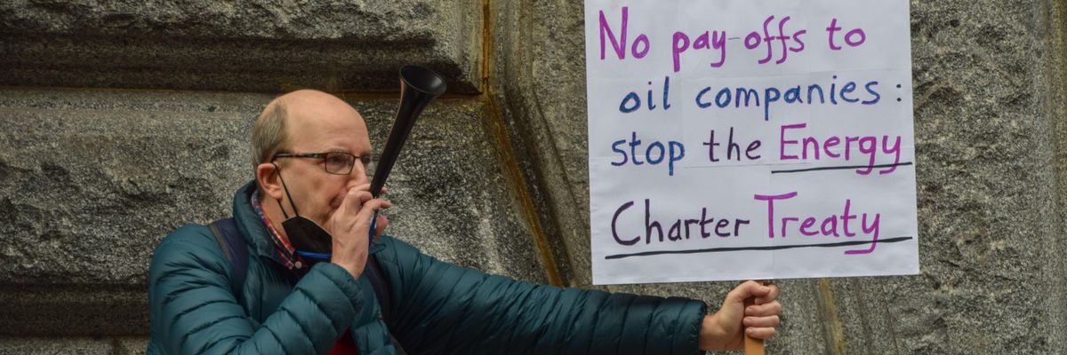 A protester holds a placard calling for the abolition of the Energy Charter Treaty during a Global Day of Action for Climate Justice demonstration in London on November 6, 2021.