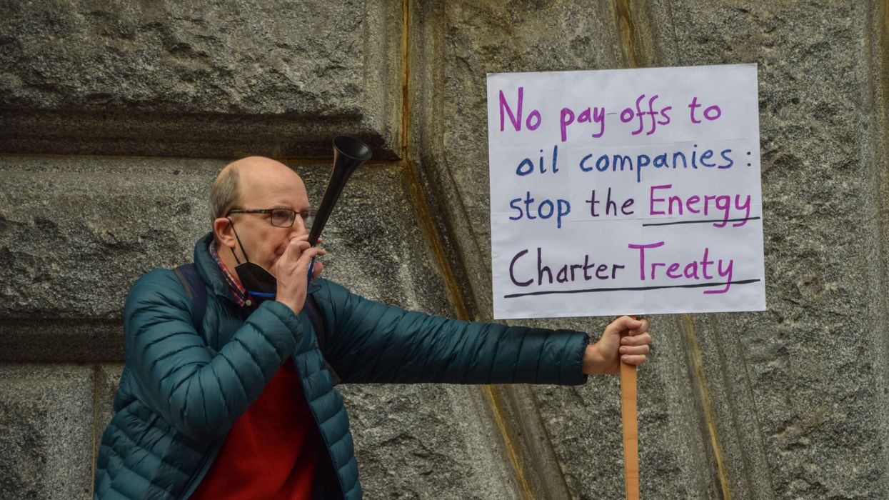 A protester holds a placard calling for the abolition of the Energy Charter Treaty during a Global Day of Action for Climate Justice demonstration in London on November 6, 2021.