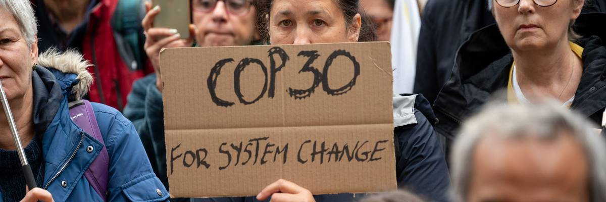 A protester holds a placard saying "COP30 for system change...