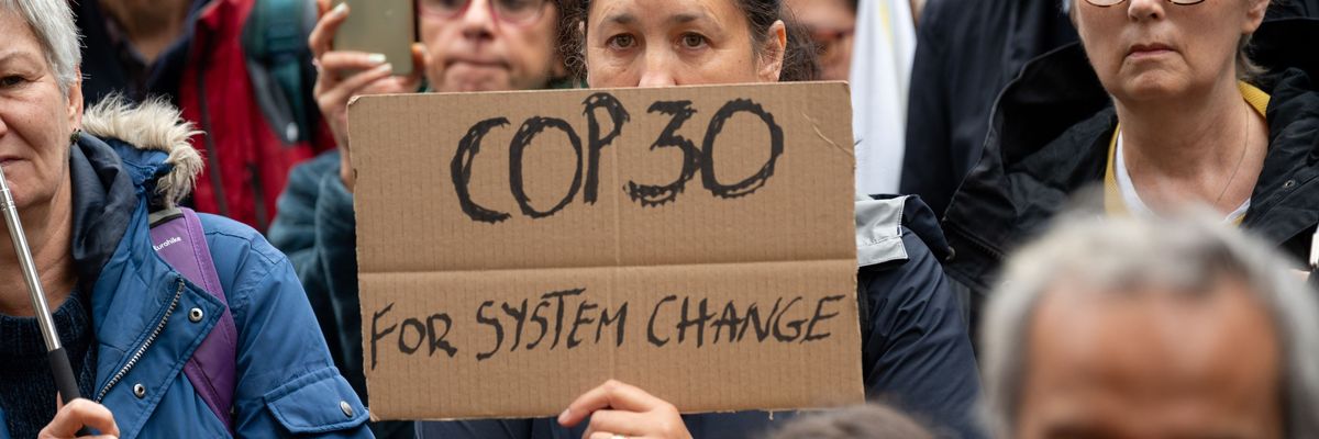 A protester holds a placard saying "COP30 for system change"