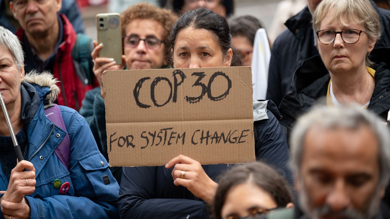 A protester holds a placard saying "COP30 for system change"