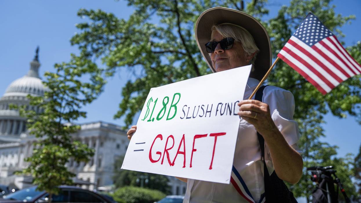 A protester holds a sign outside the US Capitol reading "$1.8B Slush Fund = Graft"