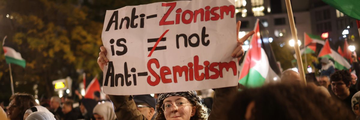 A protester holds a sign reading "Anti-Zionism Is Not Anti-Semitism" 