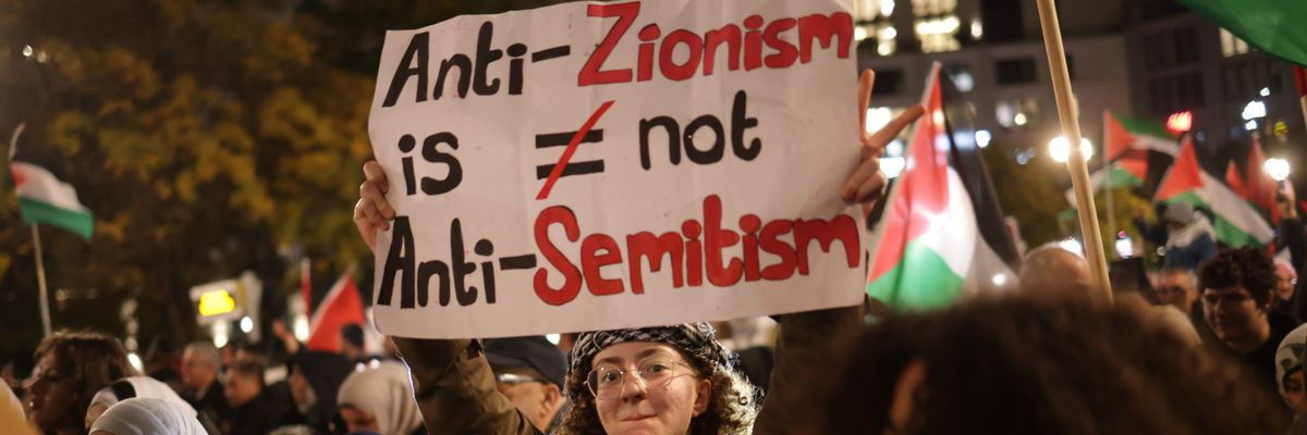A protester holds a sign reading "Anti-Zionism Is Not Anti-Semitism" 
