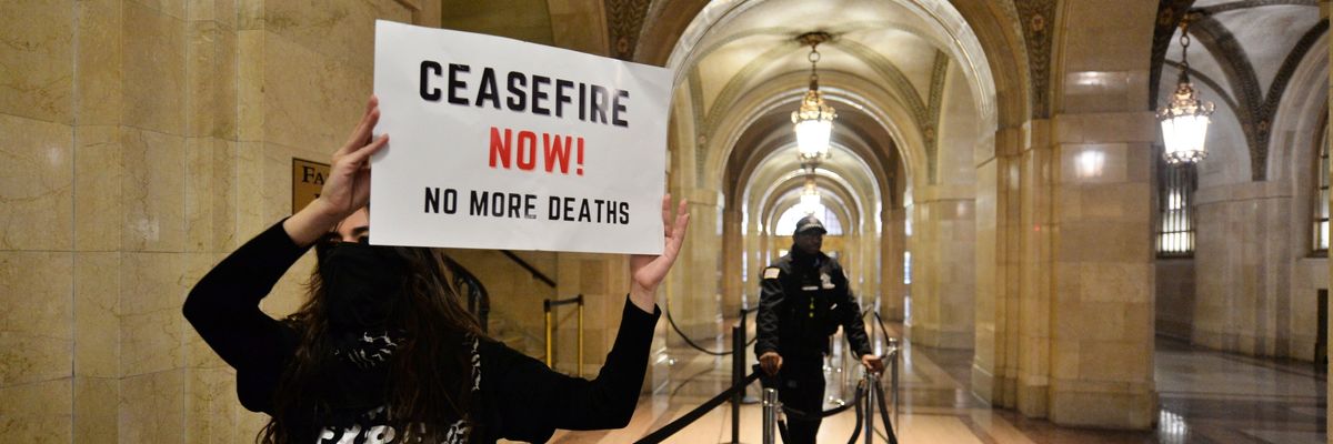 A protester holds a sign reading, "Cease-fire now! No more deaths," at Chicago City Hall.