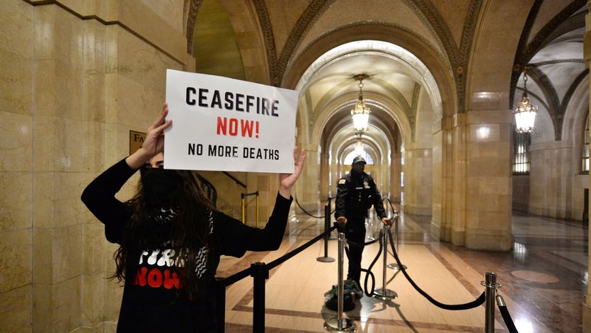 A protester holds a sign reading, "Cease-fire now! No more deaths," at Chicago City Hall.