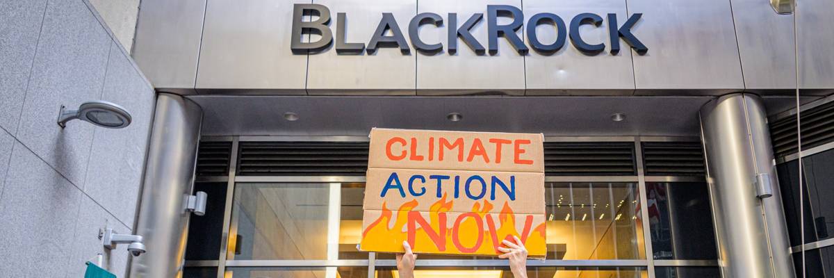 A protester holds a sign reading "Climate Action Now" at BlackRock's office in New York City