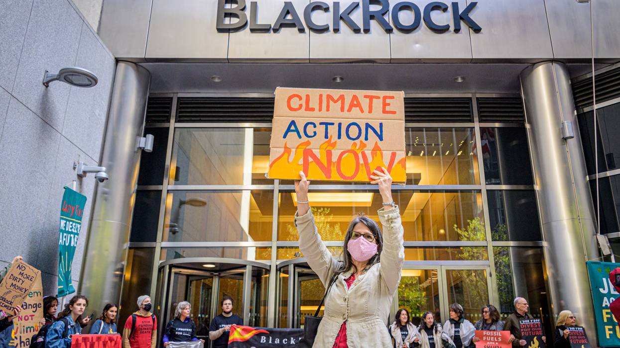 A protester holds a sign reading "Climate Action Now" at BlackRock's office in New York City