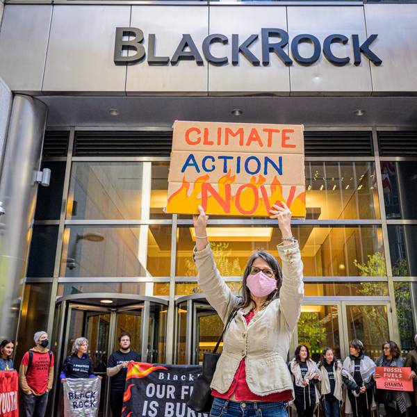 A protester holds a sign reading "Climate Action Now" at BlackRock's office in New York City
