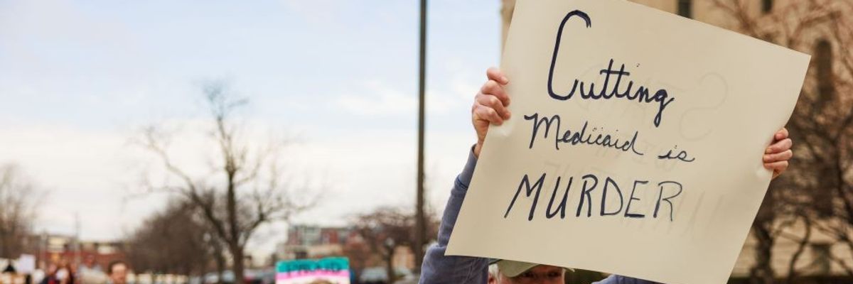 A protester holds a sign reading "Cutting Medicaid is murder."