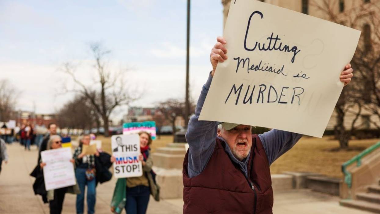A protester holds a sign reading "Cutting Medicaid is murder."