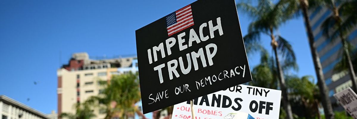 A protester holds a sign reading "Impeach Trump"