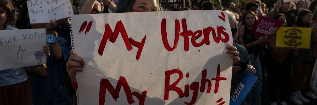 A protester holds a sign reading "My Uterus My Right" 