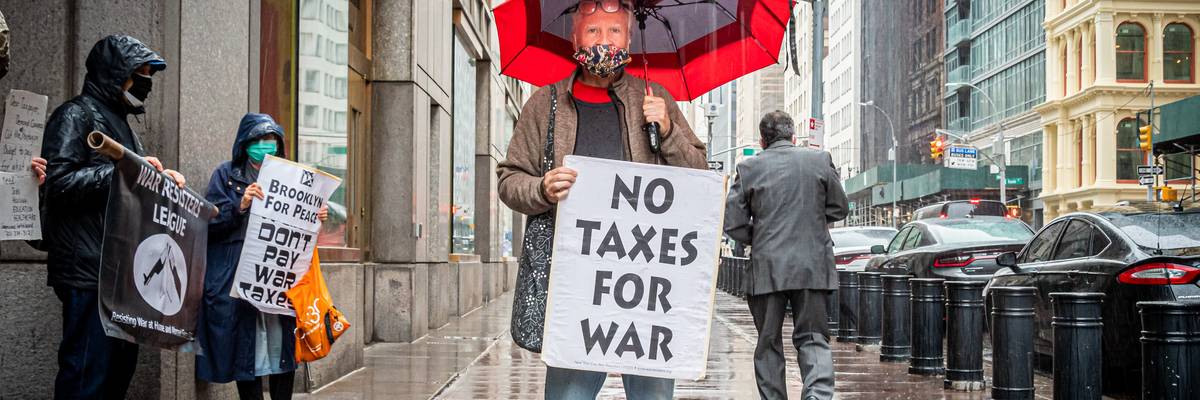 A protester holds a sign reading, "No Taxes for war."