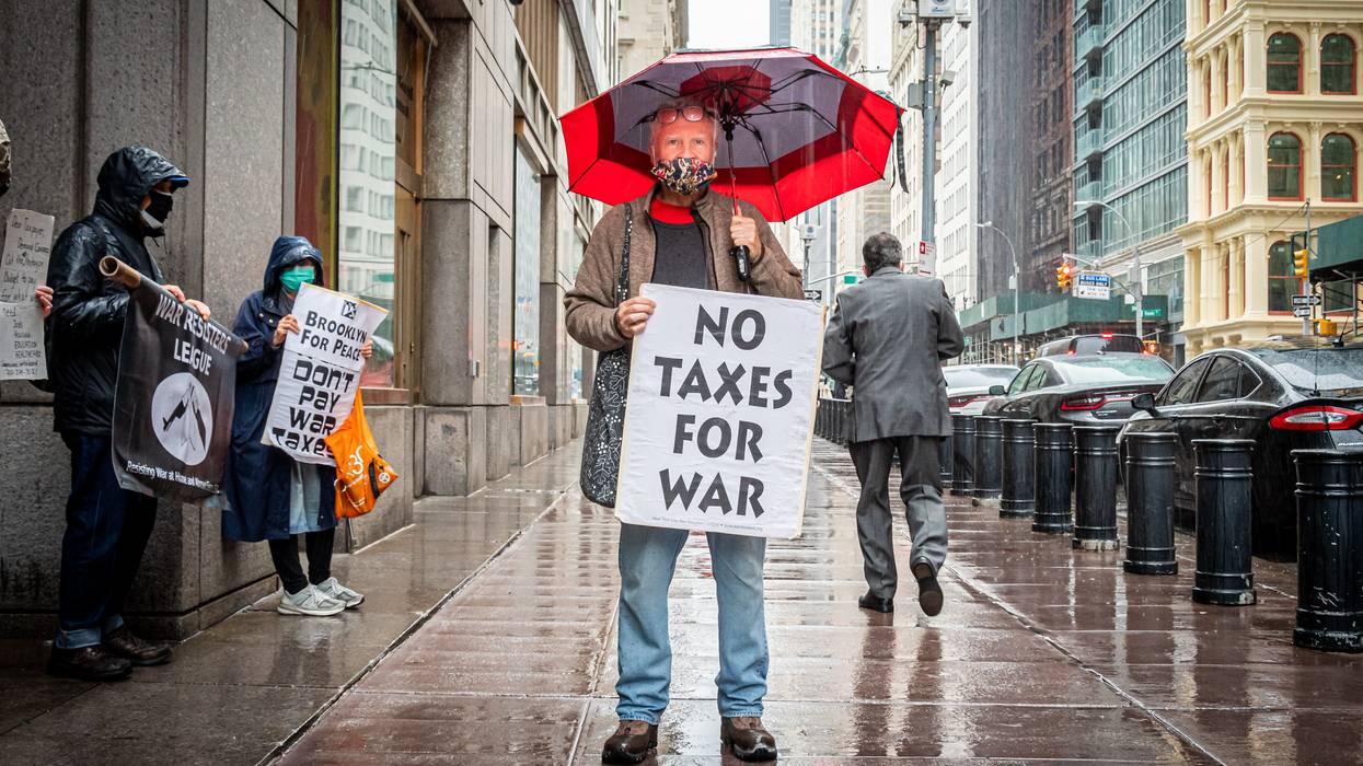 A protester holds a sign reading, "No Taxes for war."