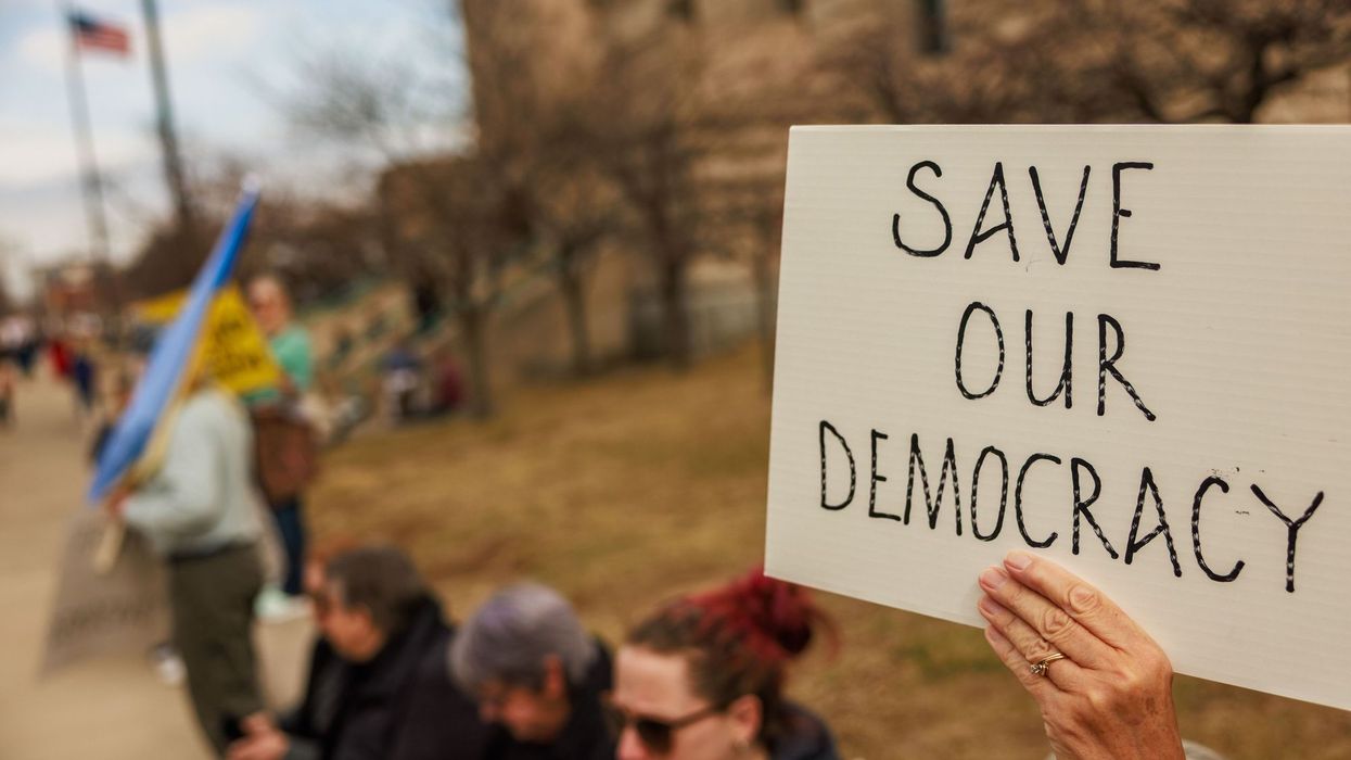 A protester holds a sign reading "Save our Democracy"...