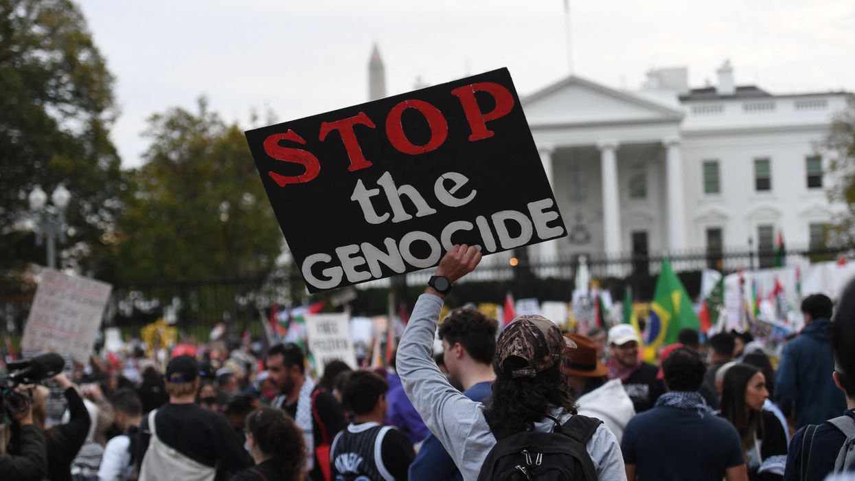 A protester holds a sign reading, "Stop the genocide" in front of the White House.