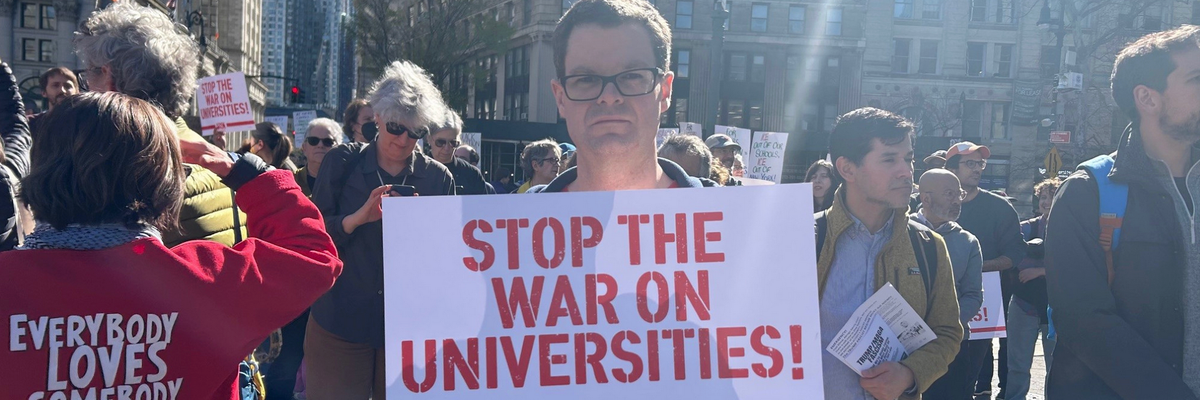 A protester holds a sign reading, "Stop the war on universities"