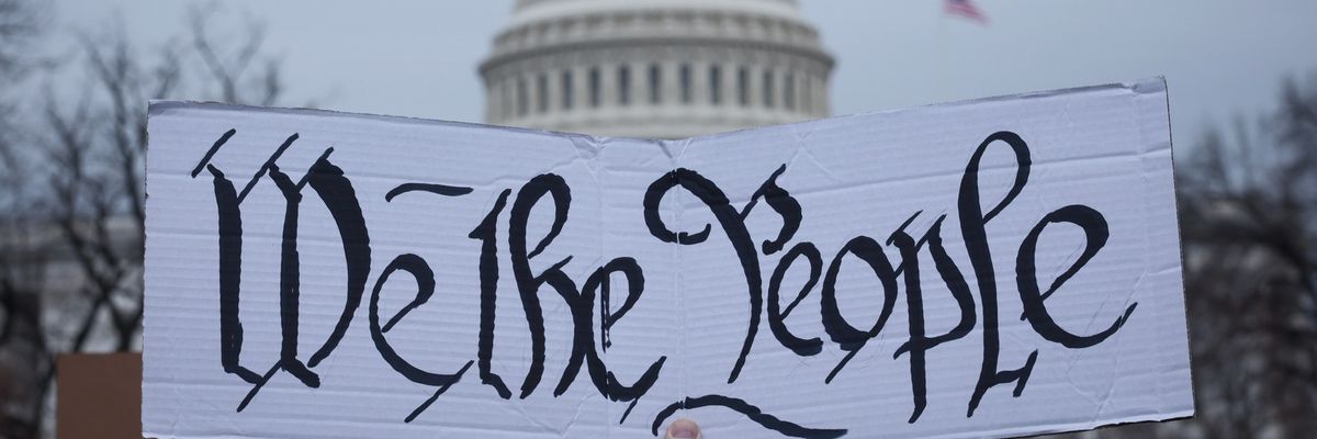 A protester holds a sign reading, "We the people" in front of the U.S. Capitol.
