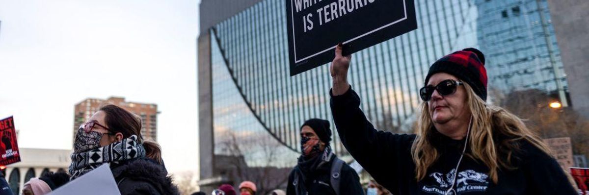 A protester holds a sign reading "White Supremacy is Terrorism" 