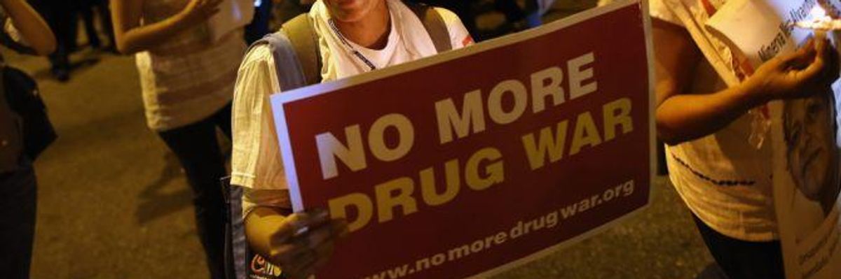 A protester holds a sign saying, "No more drug war."