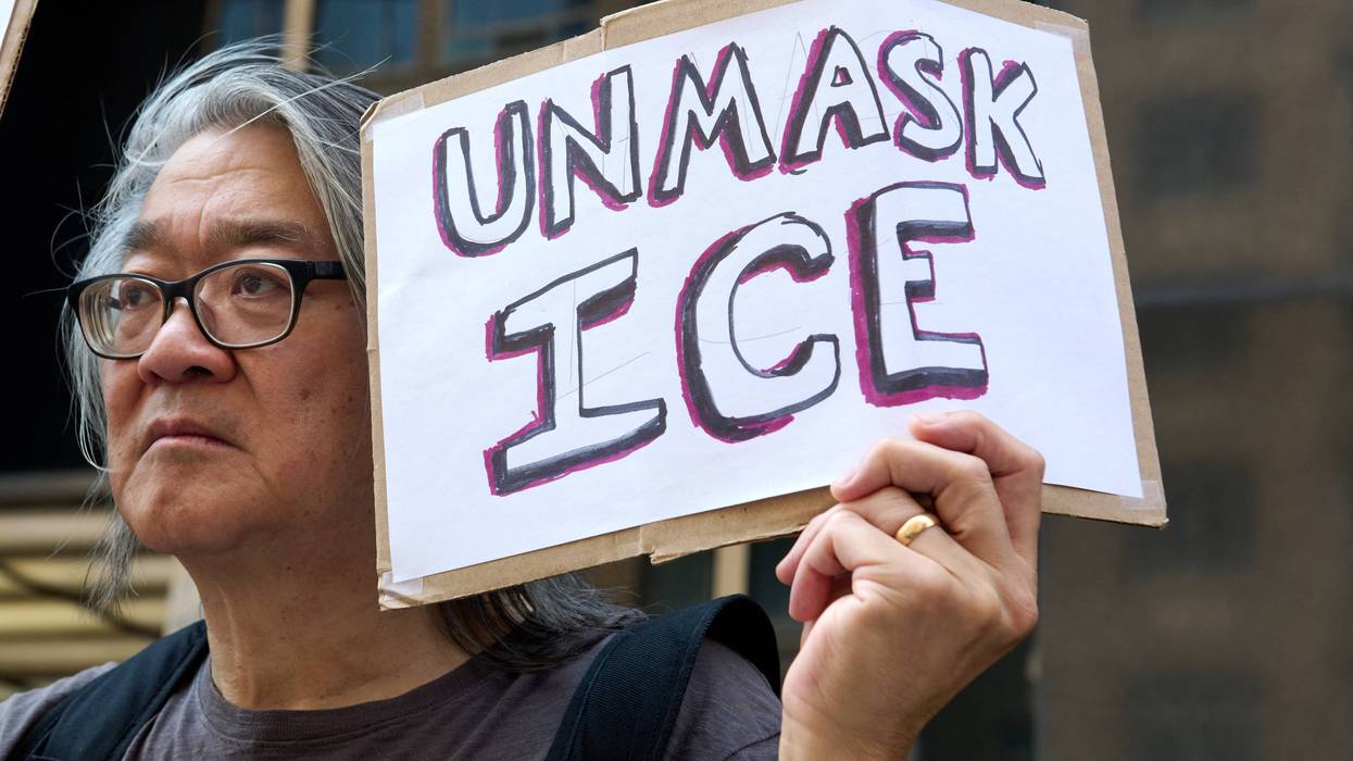 A protester holds a sign saying "Unmask ICE"