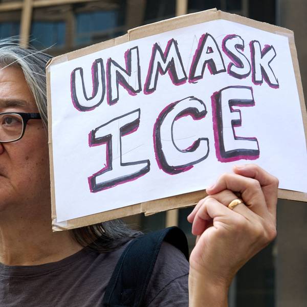 A protester holds a sign saying "Unmask ICE"