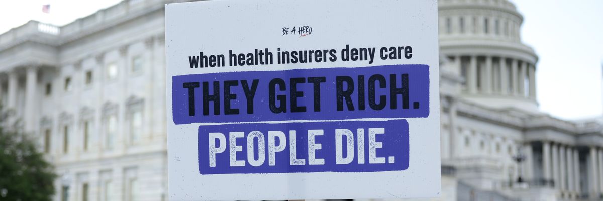 A protester holds a sign saying, "When health insurers deny care, they get rich. People die."