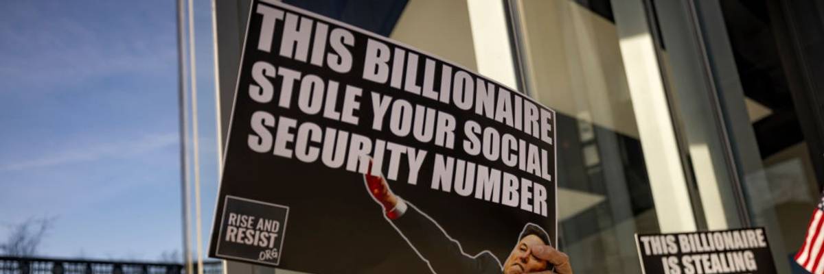 A protester holds a signs that read: "This billionaire stole your social security number"
