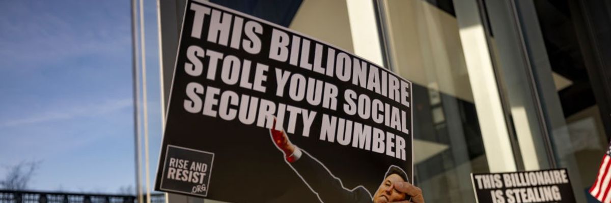 A protester holds a signs that read: "This billionaire stole your social security number"