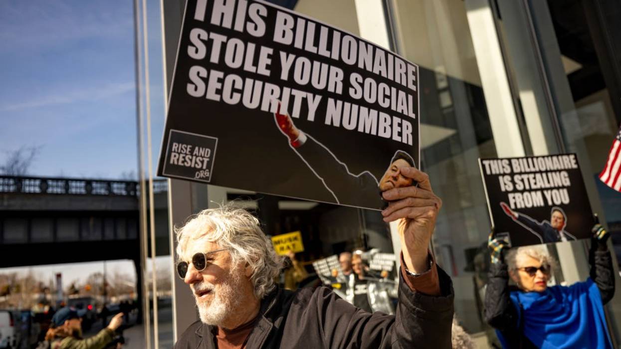 A protester holds a signs that read: "This billionaire stole your social security number"