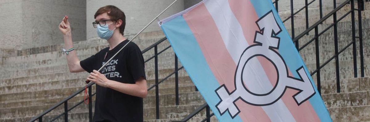 A protester holds the trans flag