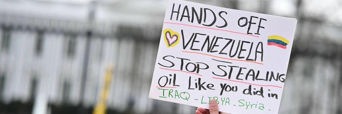 A protester holds up a sign opposing Trump's regime change in Venezuela.