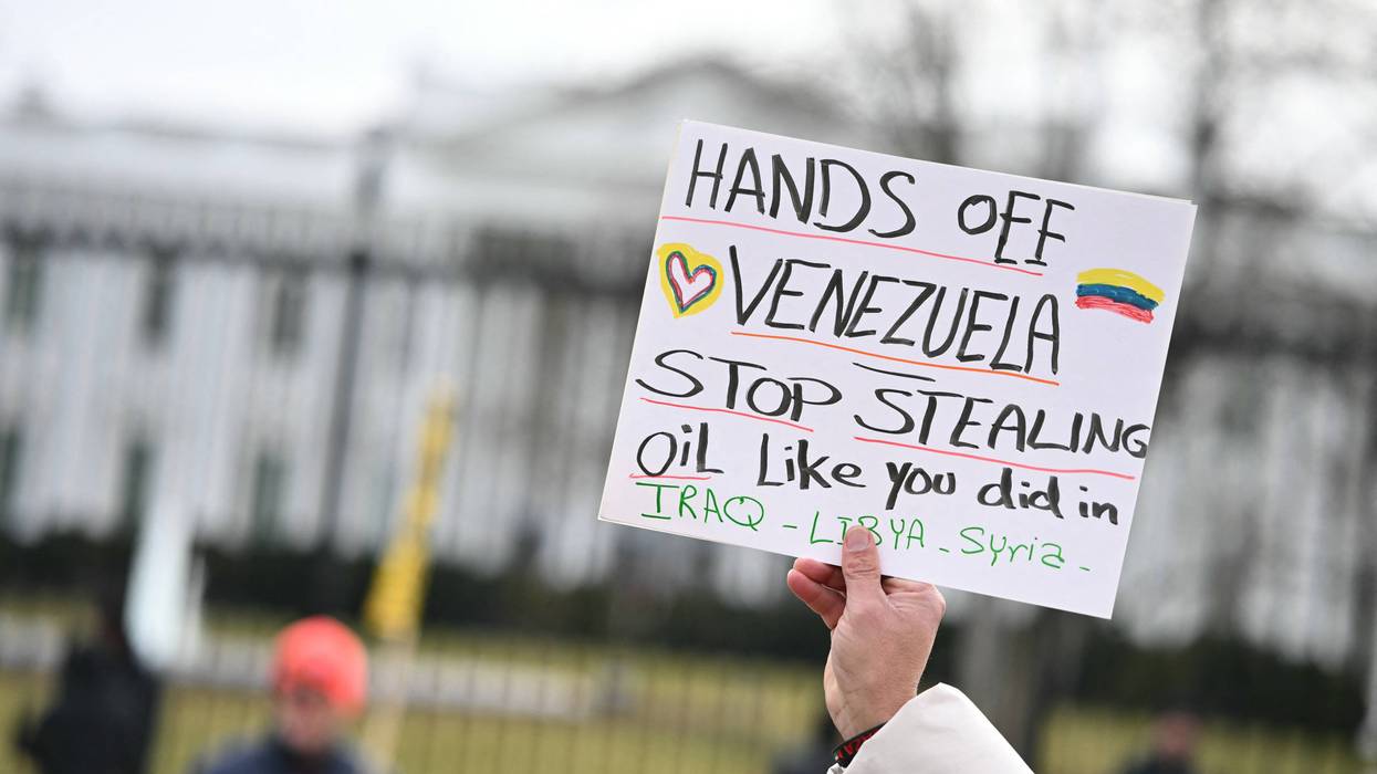 A protester holds up a sign opposing Trump's regime change in Venezuela.