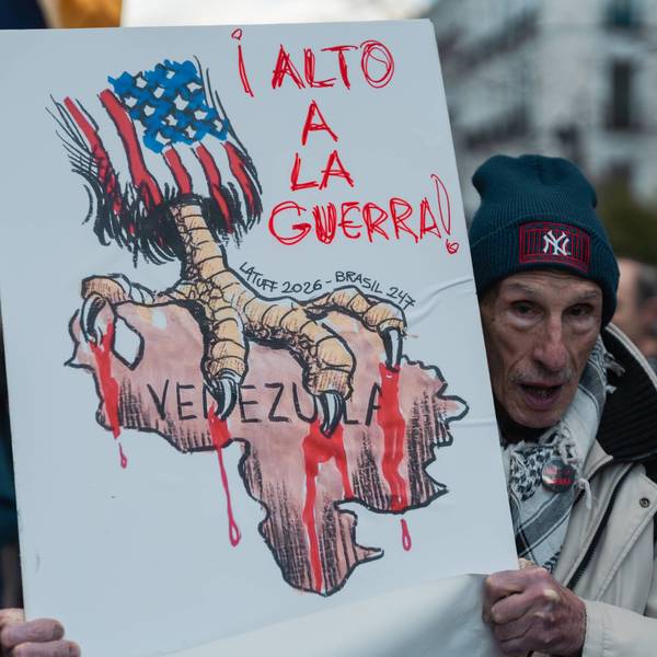 A protester in Madrid holds a sign showing the US with talons on Venezuela and the words "stop the war!"