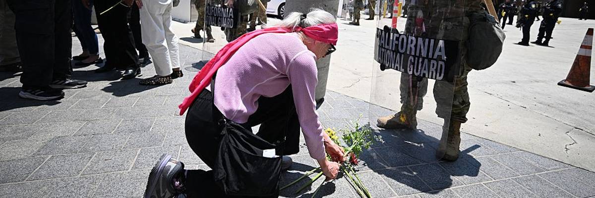 A protester places flowers at the feet of a National Guard member in LA.